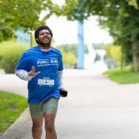 Participant running through campus showing "anchor up" with their hand